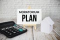 Moratorium Plan text message with calculator and house model on wooden background Royalty Free Stock Photo