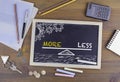 More and Less Balance. Chalkboard on wooden office desk Royalty Free Stock Photo