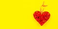 More beautiful decorative braided heart on a yellow background. The concept of love, Valentine's day. Banner.