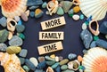 More family time and support symbol. Concept words More family time on wooden blocks. Beautiful black background. Sea stones and Royalty Free Stock Photo