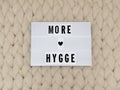 MORE HYGGE word on lightbox on knit background. Cozy compozition. Knit background. Royalty Free Stock Photo