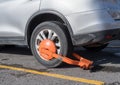 Parked car immobilized with orange parking clamp or boot Royalty Free Stock Photo