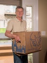 Senior man carrying a case of wine from Naked Wines into home