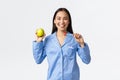 Morning, active and healthy lifestyle and home concept. Smiling beautiful asian girl showing toothbrush and green apple