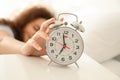 Morning of beautiful young African-American woman turning off alarm clock while lying in bed Royalty Free Stock Photo