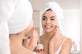 Morning of beautiful young woman applying facial cream in bathroom Royalty Free Stock Photo