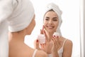 Morning of beautiful young woman applying facial cream in bathroom Royalty Free Stock Photo