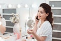 Morning of beautiful young woman applying makeup and talking by phone at home Royalty Free Stock Photo