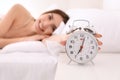 Morning of beautiful young woman turning off alarm clock while lying in bed Royalty Free Stock Photo