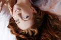 Morning in bed, a young charming red-haired woman with freckles lying in bed, hugging pillow, smiling, enjoying the Royalty Free Stock Photo