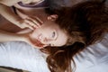 Morning in bed, a young charming red-haired woman with freckles lying in bed, hugging pillow, smiling, enjoying the Royalty Free Stock Photo