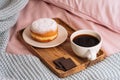 Morning breakfast in bed with aromatic and hot coffee, a doughnut in powdered sugar and three slices of chocolate on a wooden tray Royalty Free Stock Photo