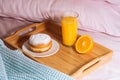 Morning breakfast in bed with fresh healthy orange juice, half orange and doughnut in powdered sugar on a wooden tray Royalty Free Stock Photo