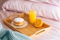 Morning breakfast in bed with fresh healthy orange juice, half orange and doughnut in powdered sugar on a wooden tray Royalty Free Stock Photo