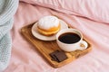 Morning breakfast in bed with fresh and hot coffee, a doughnut in powdered sugar and three slices of chocolate on a Royalty Free Stock Photo
