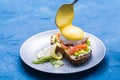 Morning and breakfast concept - Preparation of sandwich with salmon, spoon is pouring sauce on it.