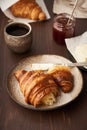 Morning breakfast with croissant on plate, cup of coffee, jam and butter. Vertical, side view