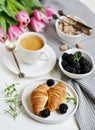 Morning breakfast with cup of coffee, croissants, fresh berries and pink flowers tulips Royalty Free Stock Photo