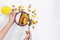 Morning breakfast. Female hands hold a spoon over a bowl with homemade yogurt and cornflakes, raisins, almonds on white background Royalty Free Stock Photo