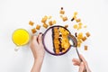 Morning breakfast. Female hands hold a spoon over a bowl with homemade yogurt and cornflakes, raisins, almonds on white background Royalty Free Stock Photo