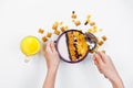 Morning breakfast. Female hands hold a spoon over a bowl with homemade yogurt and cornflakes, raisins, almonds on white background Royalty Free Stock Photo