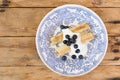 Morning breakfast with french crepes, fresh blueberry, yogurt on a plate on wooden table background.