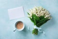 Morning breakfast from fresh coffee cup and spring bouquet of flowers lily of the valley with empty greeting card top view Royalty Free Stock Photo