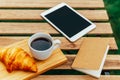 Morning Breakfast In Green Garden With French Croissant, Coffee Cup, Orange Juice, Tablet and Notes Book On Wood Table Royalty Free Stock Photo