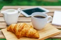 Morning Breakfast In Green Garden With French Croissant, Coffee Cup, Orange Juice, Tablet and Notes Book On Wood Table Royalty Free Stock Photo