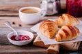 Homemade baked croissants with jam and coffee on wooden rustic background Royalty Free Stock Photo