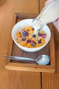 morning breakfast, little girl hand with cornflakes cereal, strawberry, blackberry and milk in a white bowl Royalty Free Stock Photo