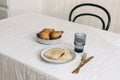 Morning breakfast with pears fruit composition. Bread toast, folded newspapers and glass of water on white linen table