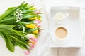 Morning breakfast in spring with a cup of black coffee with milk in the pastel colors, a bouquet of fresh yellow and pink tulips o Royalty Free Stock Photo