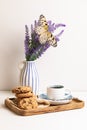Morning breakfast, still life A wooden tray, a cup of coffee, chocolate cookies and a large butterfly on a bouquet