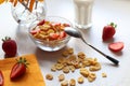 Morning Breakfast of strawberries and cornflakes on the kitchen table with a glass of milk and a bouquet of flowers, yellow napkin