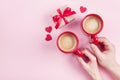 Morning breakfast for Valentines day. Couple holding cups of coffee, gift box and red hearts on pink background top view. Flat lay Royalty Free Stock Photo