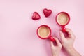 Morning breakfast for Valentines day. Couple holding cups of coffee and red hearts on pink background top view. Flat lay Royalty Free Stock Photo