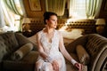 morning of bride. beautiful woman in lace robe sitting on couch in room. Royalty Free Stock Photo