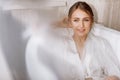 Morning of the bride. Happy beautiful young woman is wearing in a white long veil, robe and underwear sitting laughing and having Royalty Free Stock Photo