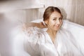 Morning of the bride. Happy beautiful young woman is wearing in a white long veil, robe and underwear sitting laughing Royalty Free Stock Photo