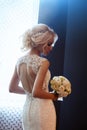 Morning bride. A woman in a white wedding dress holding a bouquet of flowers in her hands. Beautiful blonde girl getting ready for Royalty Free Stock Photo