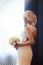 Morning bride. A woman in a white wedding dress holding a bouquet of flowers in her hands. Beautiful blonde girl getting ready for Royalty Free Stock Photo