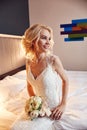 Morning bride. A woman in a white wedding dress holding a bouquet of flowers in her hands. Beautiful blonde girl getting ready for Royalty Free Stock Photo