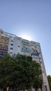 In the morning, a bright sun appears from behind a high-rise apartment building against a blue sky Royalty Free Stock Photo