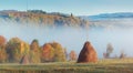 Morning Carpathian hills with fog and haystacks. Royalty Free Stock Photo