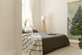 Morning coffee on a bed that is dresses in gray linen in a natural style bedroom interior with an evergreen tree poster on a wall.