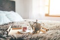 Morning `coffee in bed` still life. Cozy bedroom shot with coffee pot and cup on the fir bed blanket with magic background window Royalty Free Stock Photo