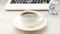 Morning coffee black hot espresso with steam in white cup, saucer on wooden table, clock, notebook Royalty Free Stock Photo