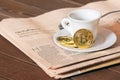 Morning coffee of the broker at the exchange, black coffee and bitcoin on the background of the stock quotes chart on newspaper