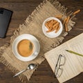 Morning coffee - a cup, a notebook, a pencil, glasses and a smartphone on a brown wooden table with a napkin Royalty Free Stock Photo